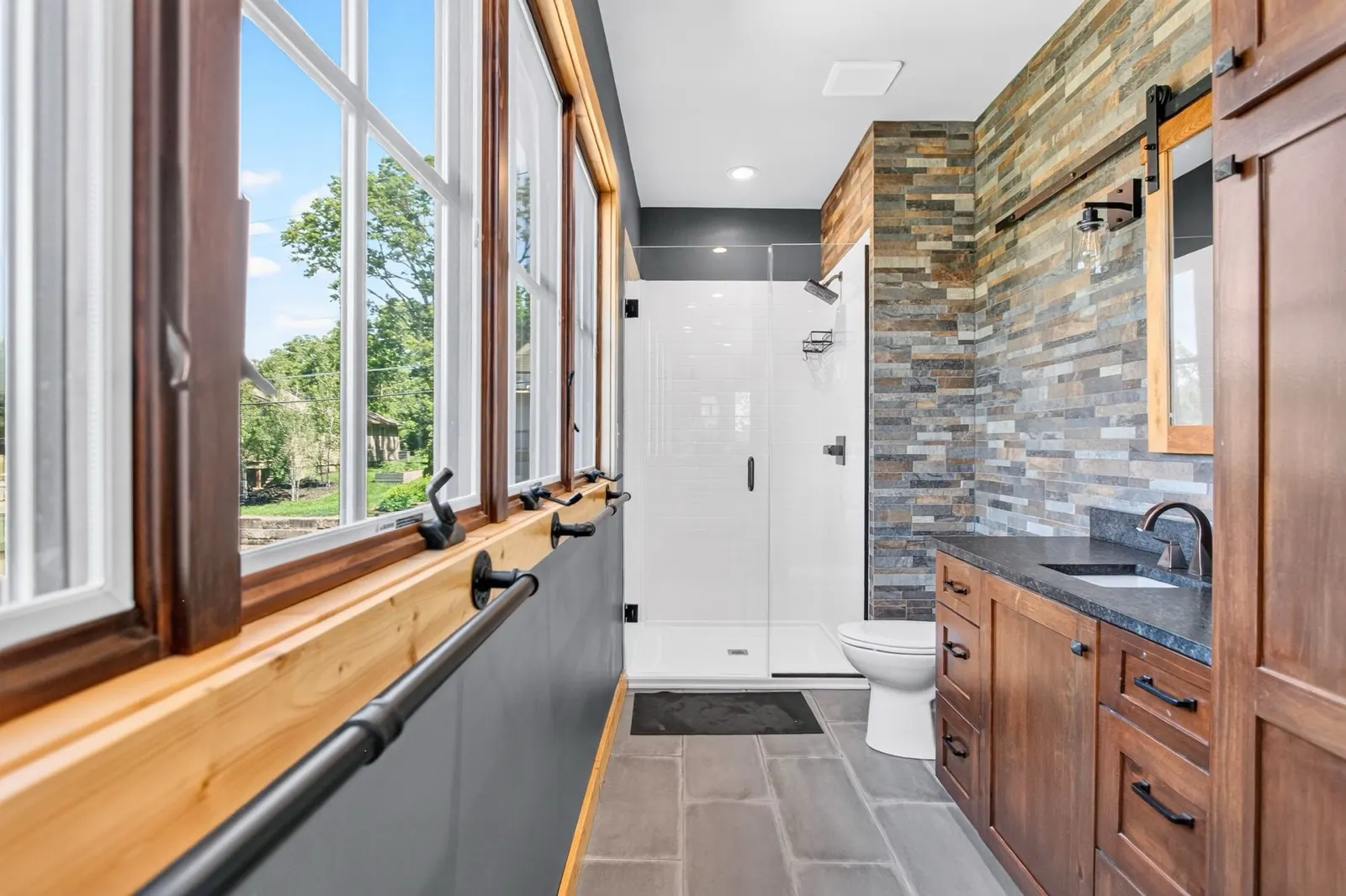 Bathroom with stacked stone accent wall and glass shower at 31 H Street, Lake Lotawana