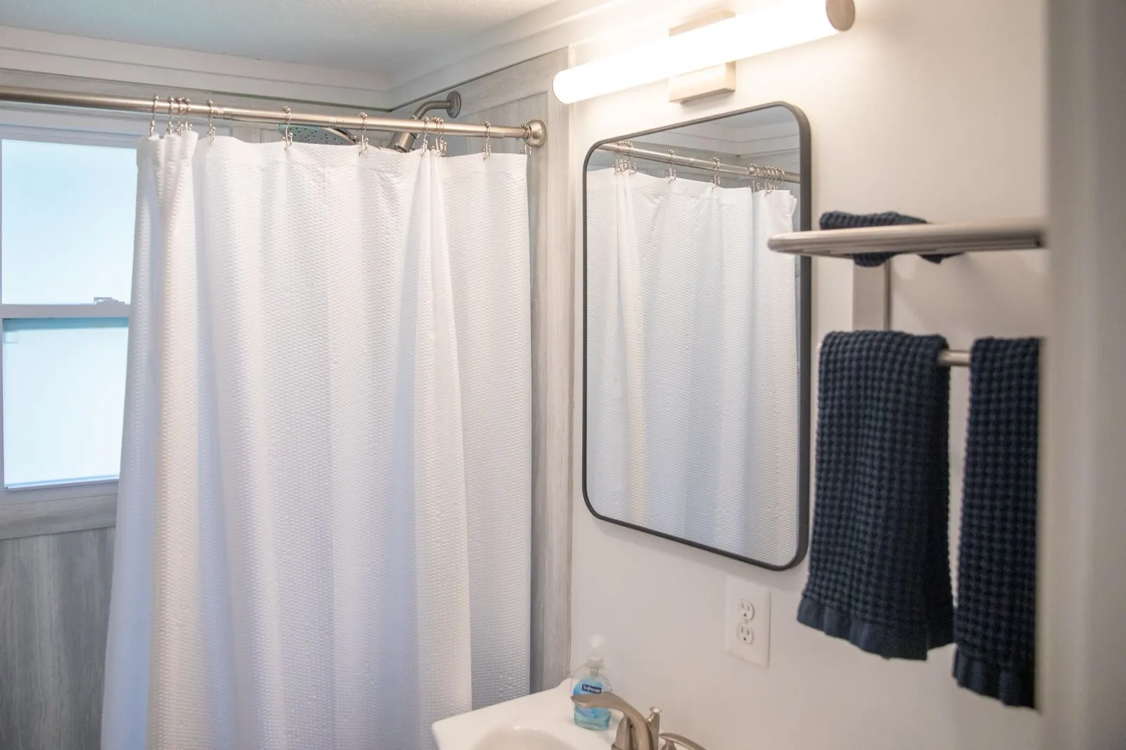 Bathroom with shower curtain and navy towels at 61 H Street, Lake Lotawana