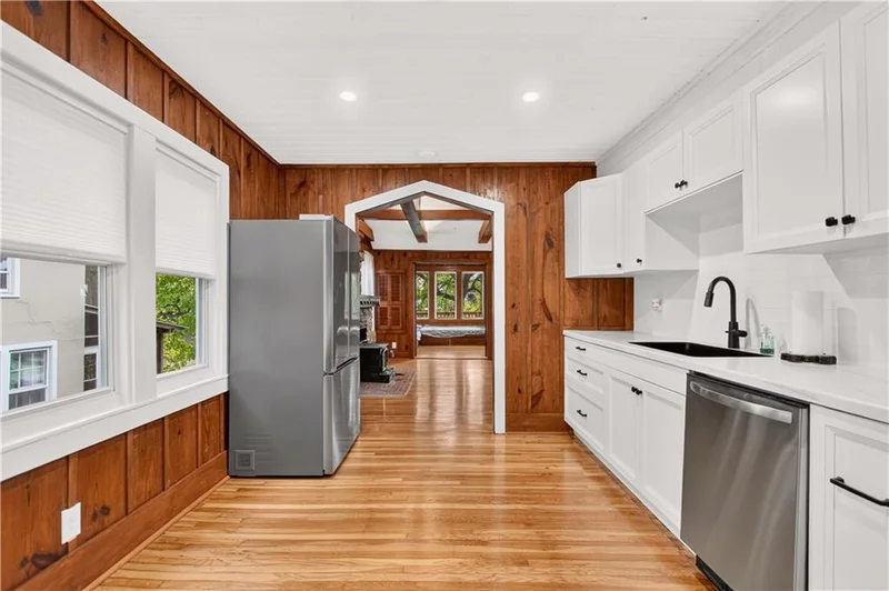 Brand-new kitchen with white cabinets, stainless appliances, and wood-paneled walls