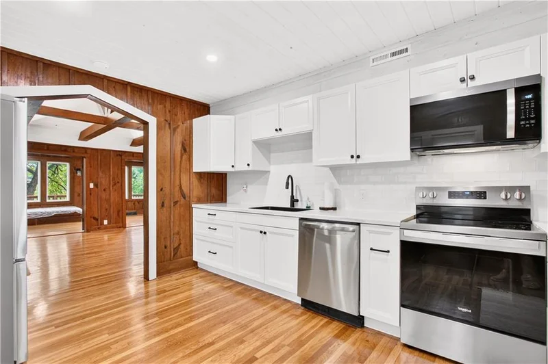 Kitchen with white cabinetry and a stainless range, opening to the living area