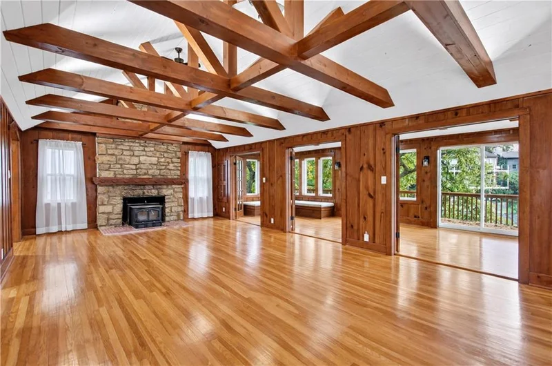 Great room with exposed wood beams and a stone fireplace