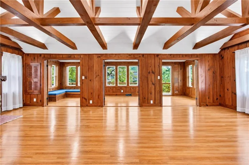 Great room lined with wood paneling, windows, and doors