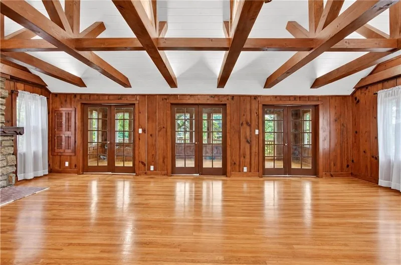 Vaulted great room with exposed beams and lake-facing windows